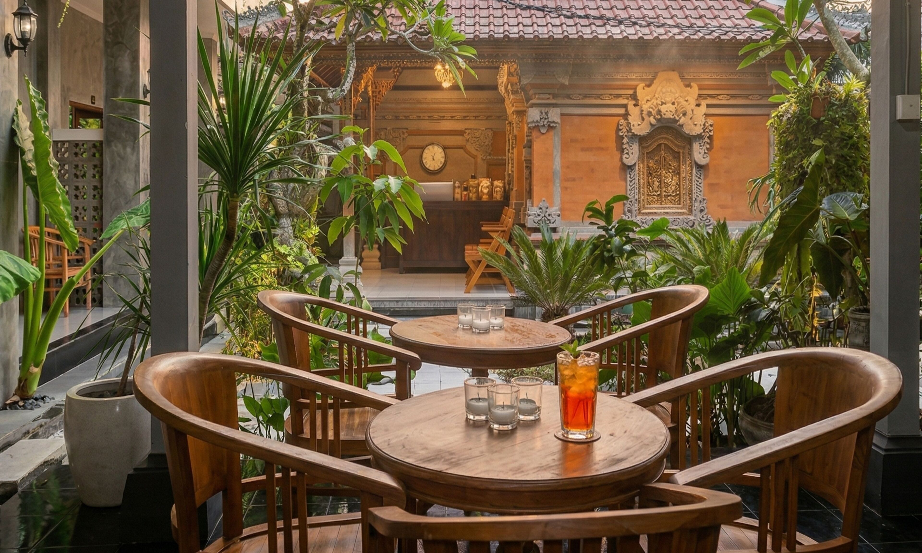 A wooden table with chairs, surrounded by potted plants, in a courtyard with traditional architecture.