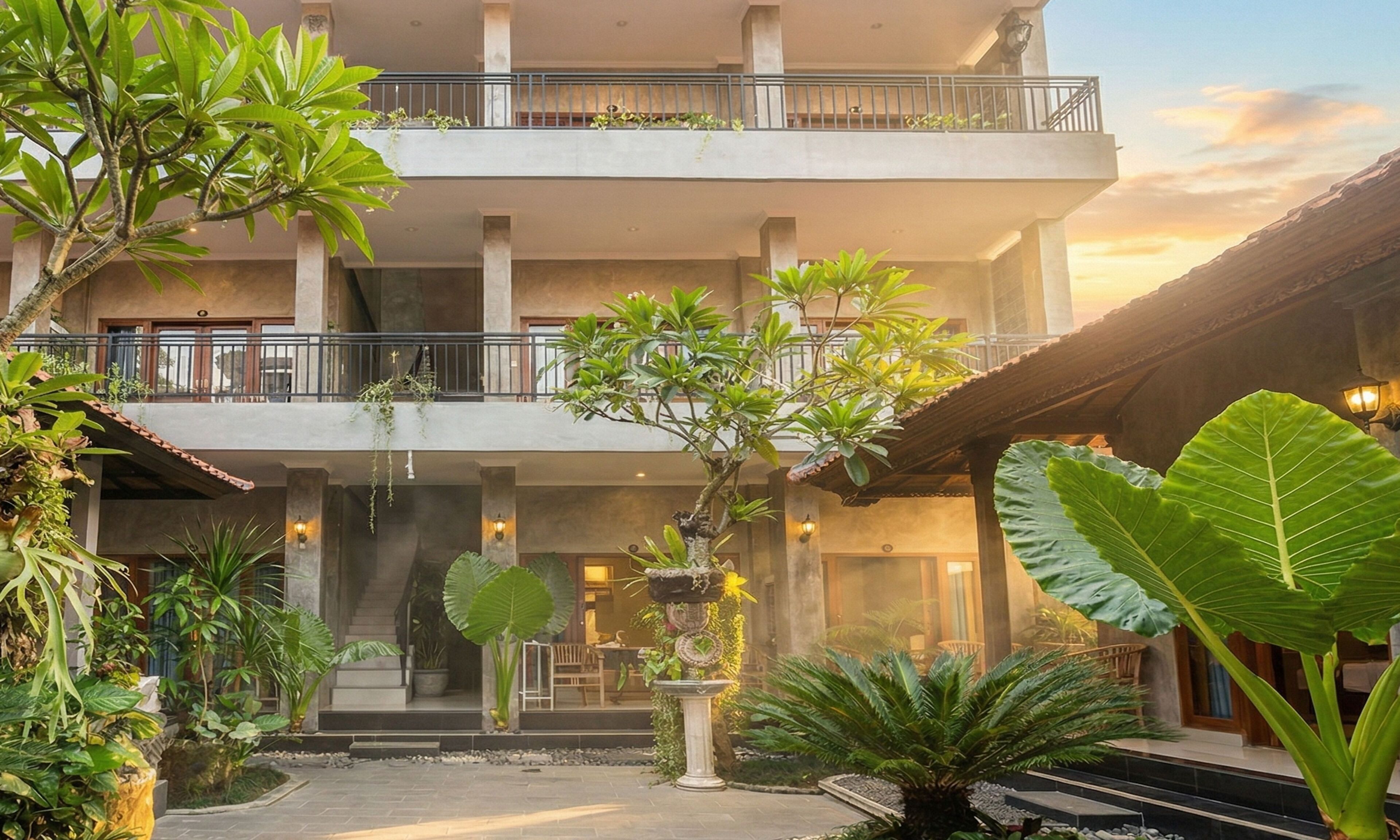 A multi-story hotel with a central courtyard, balconies, and lush greenery.