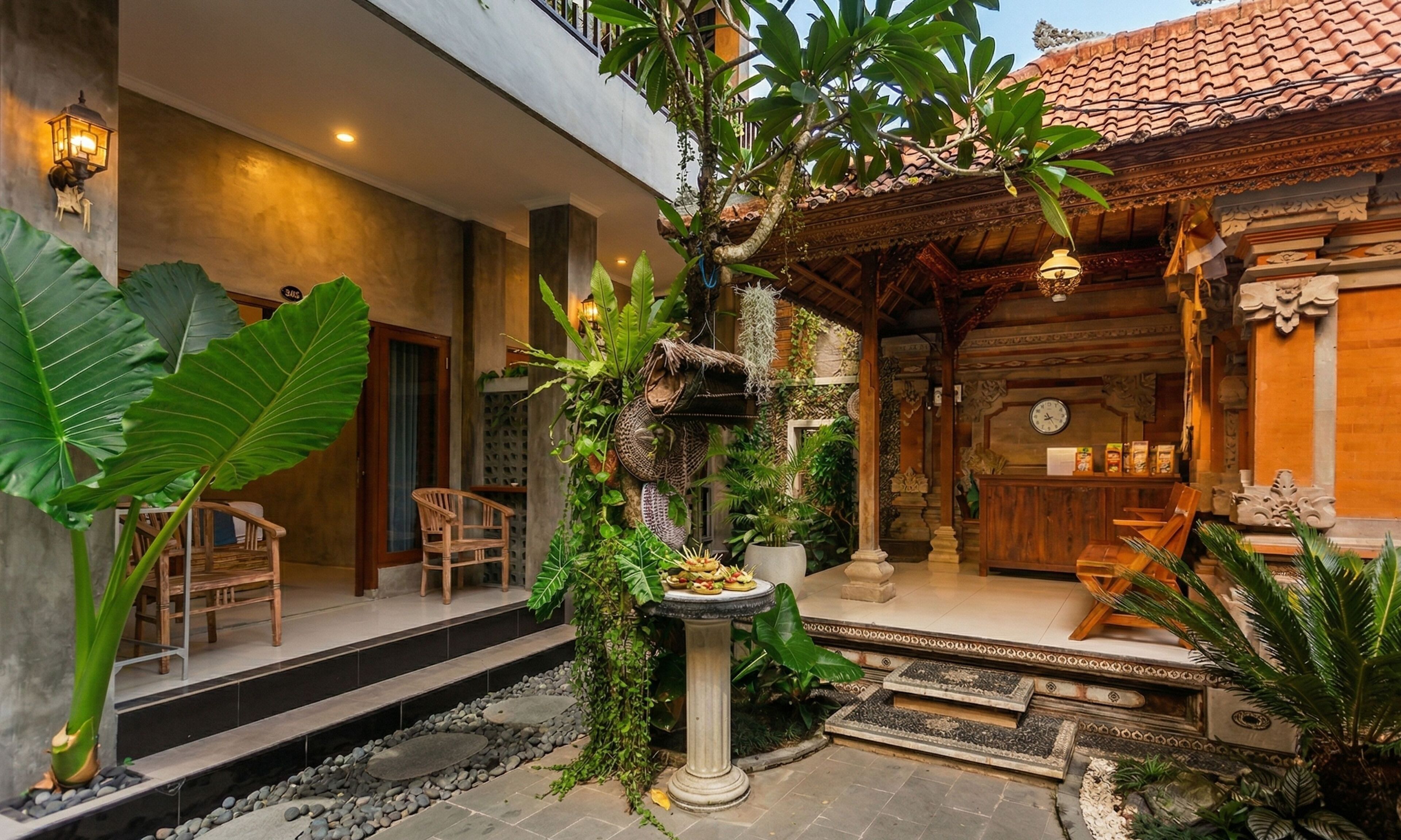 A traditional wooden building with a tiled roof, a stone pathway, and a small garden area with large leaves and a birdcage.