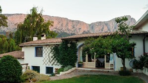 Uma casa de dois andares com telhado de telhas, varanda frontal e um pequeno jardim.