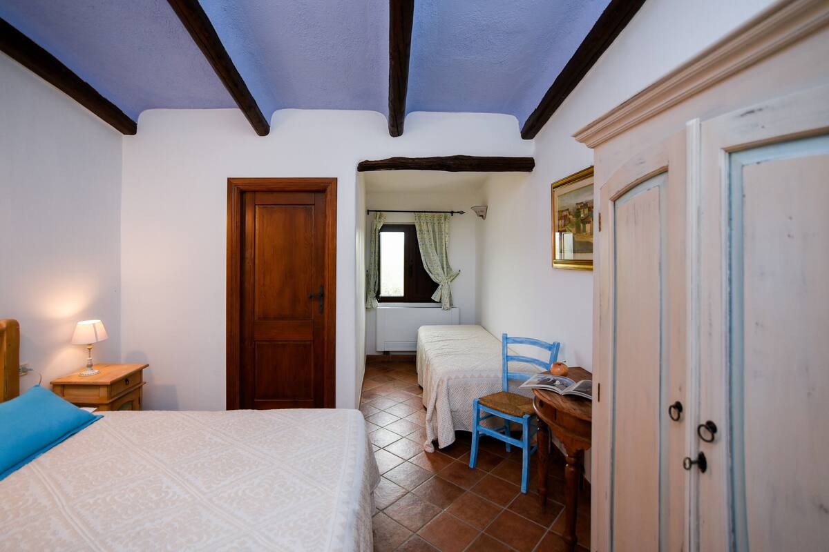 Un dormitorio con dos camas, una puerta de madera, una ventana con cortinas, una silla y un escritorio.