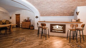 Um interior rústico com balcão de madeira, banquetas e teto de tijolos.
