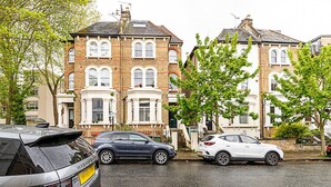 A row of traditional brick townhouses with parked cars in front. - Cosy and Modern Battersea Home (London)