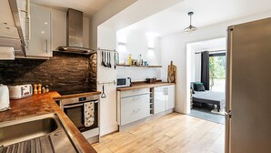 A modern kitchen with a stone backsplash, wooden countertop, and stainless steel appliances. - Cosy and Modern Battersea Home (London)