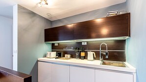 Eine moderne Küche mit weißen Schränken, einer Edelstahlspüle und einer Holzausziehtafel.
