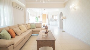 Ein Wohnzimmer mit einem beigefarbenen Ecksofa, einem Holztisch und einer Chandelier.