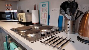 Una cocina con estufa, microondas y diversos utensilios.