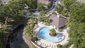An aerial view of a residential area with a circular swimming pool surrounded by lounge chairs and palm trees. - Your VIP Home in Orlando - Disney 25106 (Kissimmee)