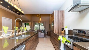 A modern kitchen with a central island, stainless steel appliances, and a view to the outdoors. - Luxury 3bdr House Near Disney 7527 (Kissimmee)