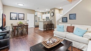 A modern living room with a sofa, coffee table, and dining area with chairs and a table.