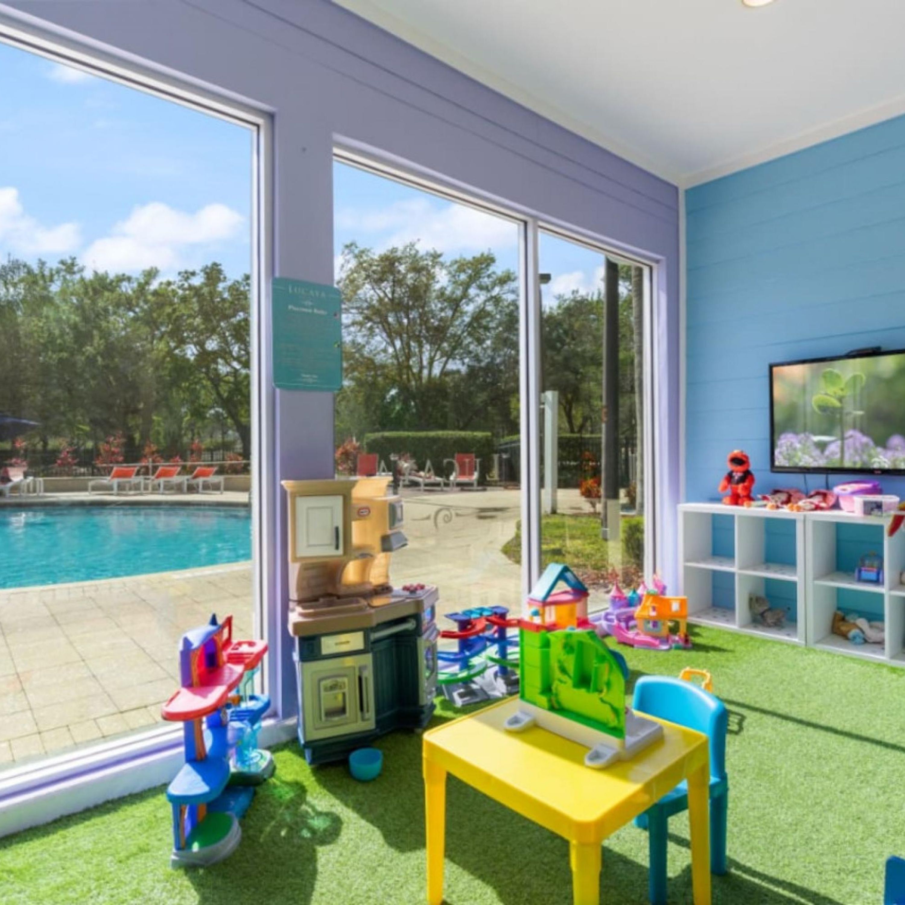 A children's play area with a pool view, a vending machine, and a TV on the wall.