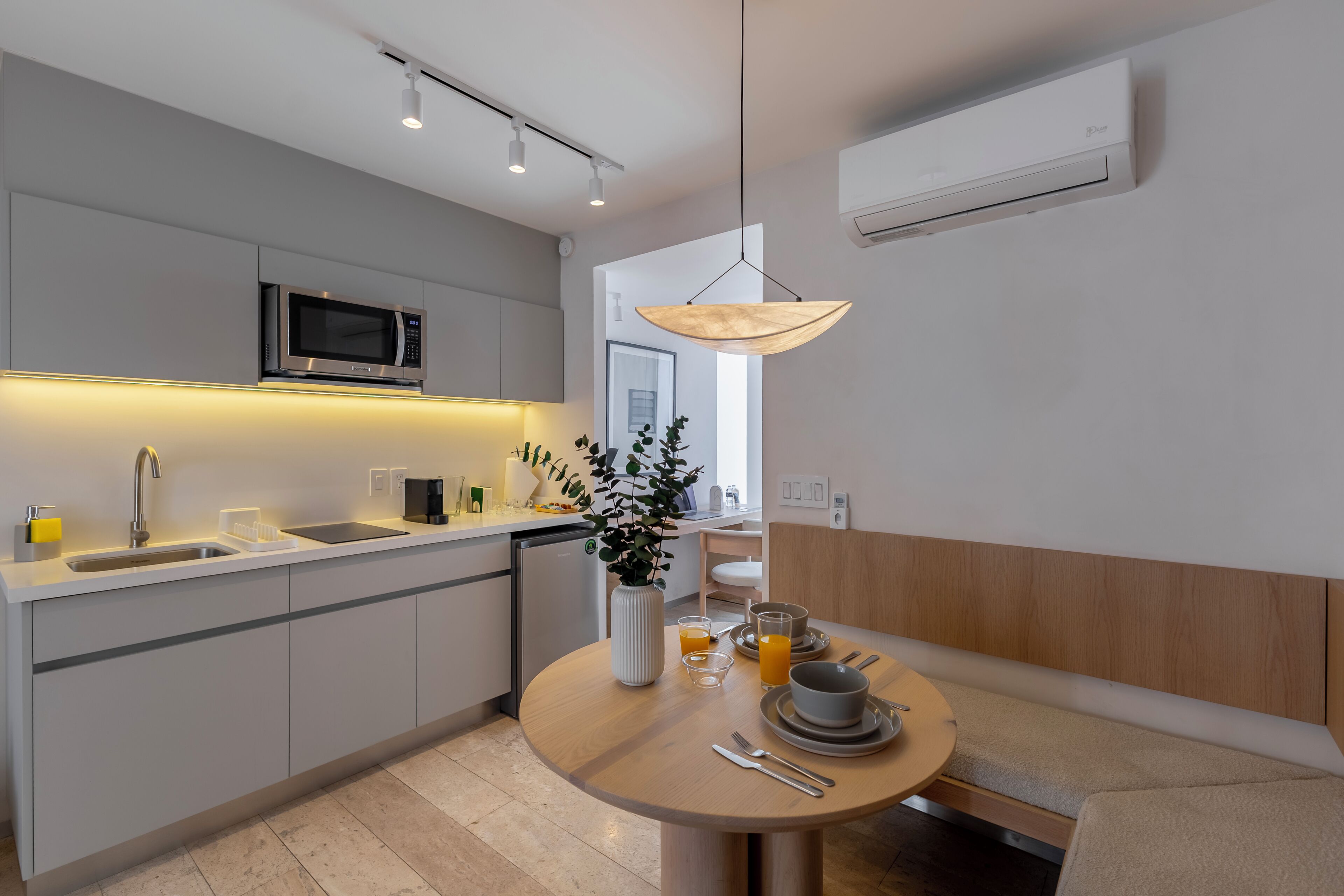 Een moderne keuken met een ingebouwde magnetron, een spoelbak en een eethoek met een ronde tafel voor twee personen.