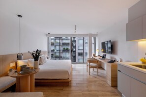 A modern hotel room with a bed, bedside table, desk, and a view of the cityscape through large windows. - Capitalia Antara Polanco (Mexico City)