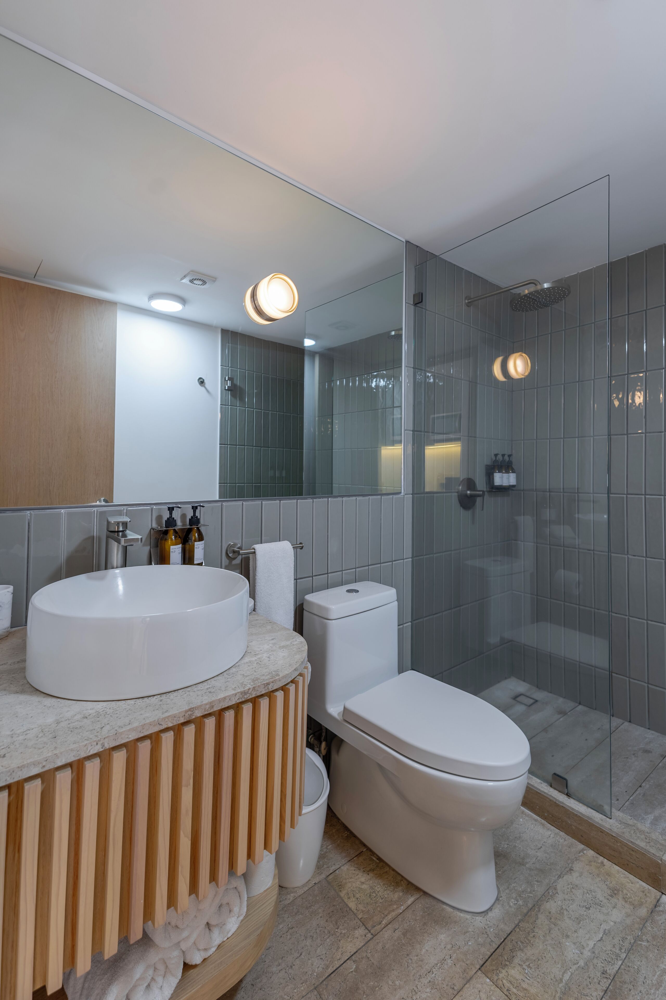 A modern bathroom with a large white sink, a toilet, and a glass-enclosed shower area.