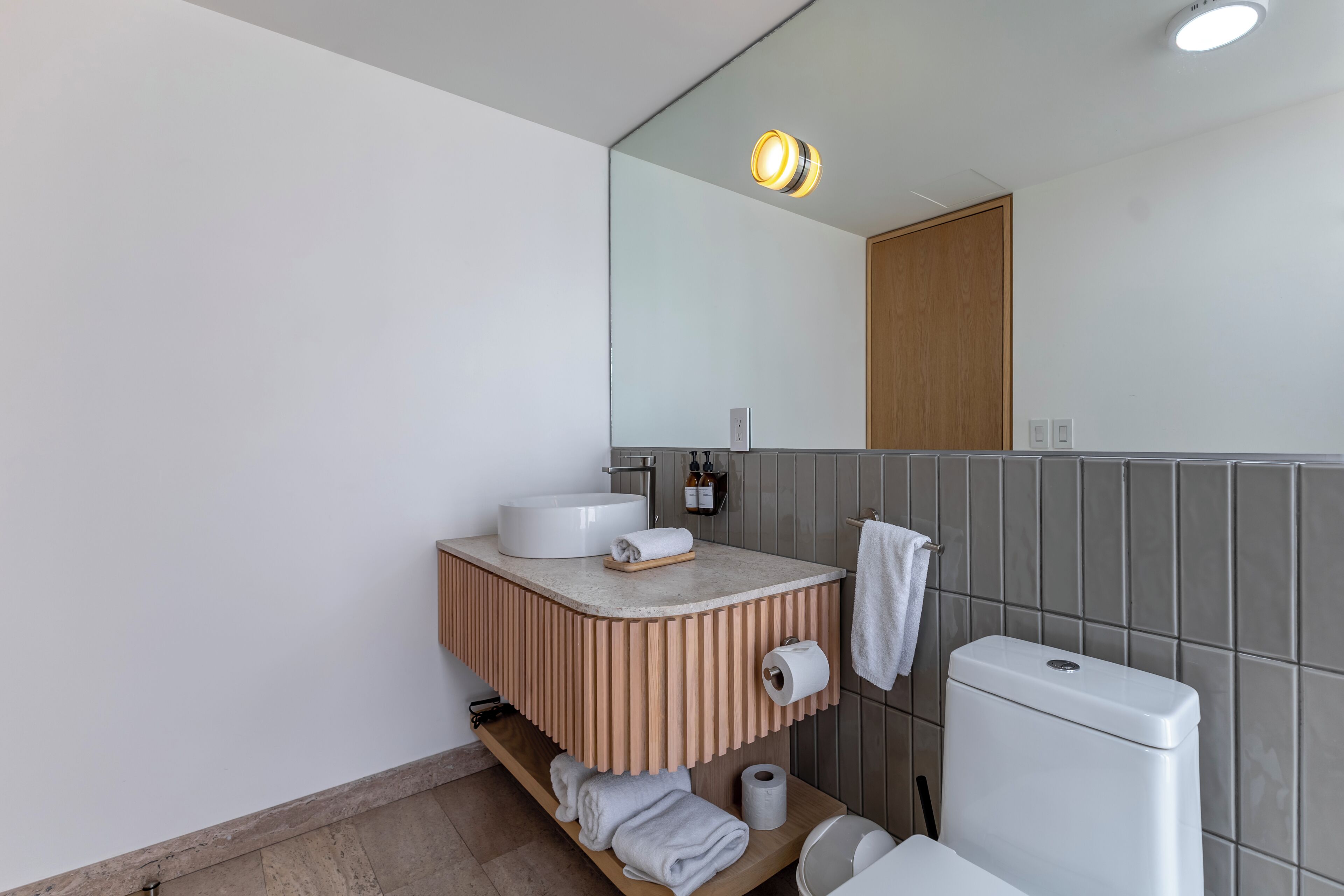 A modern bathroom with a vanity, mirror, toilet, and towel rack.