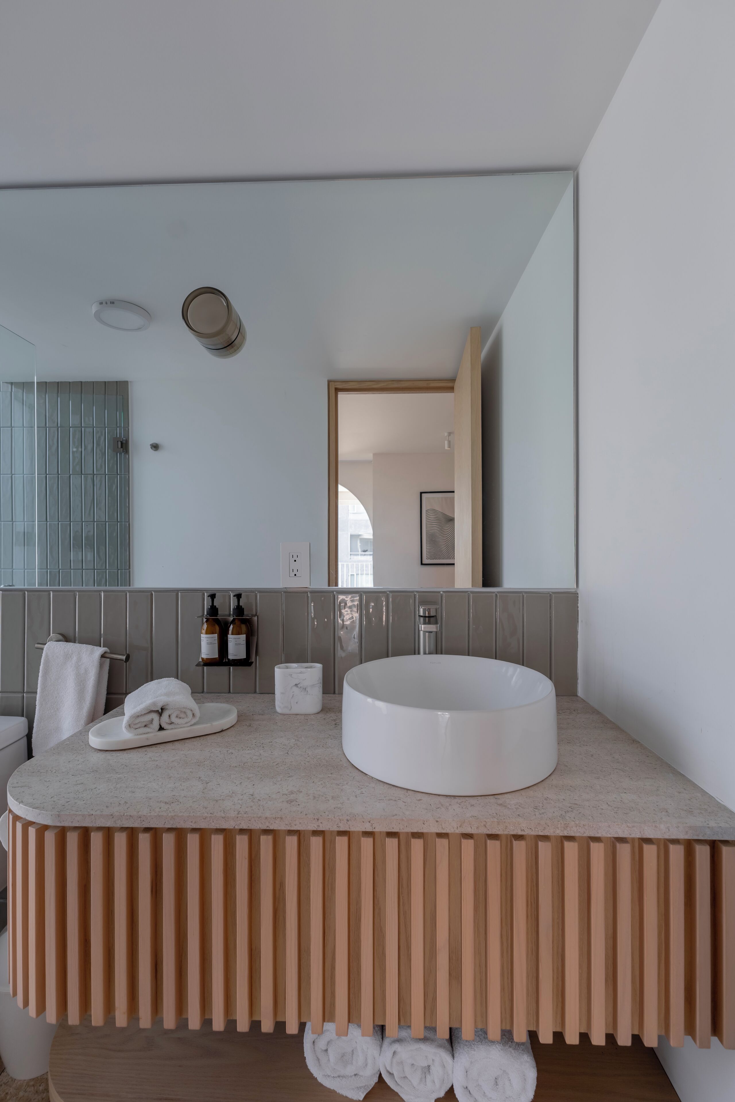 Une salle de bain moderne avec un lavabo rond, un porte-serviettes et un miroir.