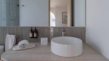 Une salle de bain moderne avec un lavabo rond, un porte-serviettes et un miroir.