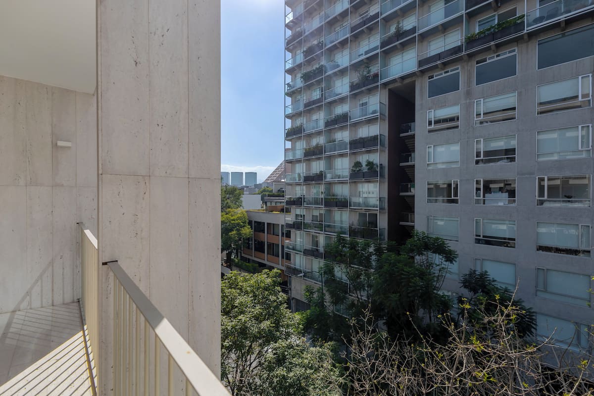 A high-rise building with multiple balconies, large windows, and a view of surrounding buildings.