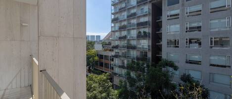 A high-rise building with multiple balconies, large windows, and a view of surrounding buildings.