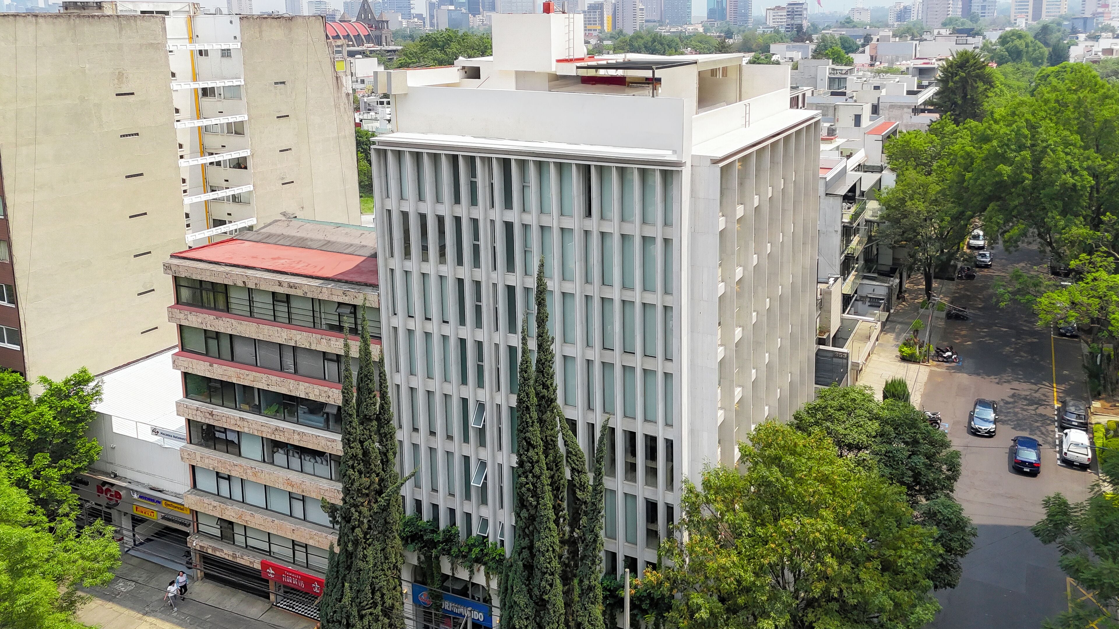 A multi-story building with a modern architectural design, featuring a grid of windows and a flat roof.