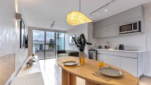 A modern kitchen with a wooden dining table, a microwave, and a glass of orange juice.