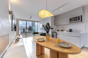 A modern kitchen with a wooden dining table, a microwave, and a glass of orange juice. - Capitalia Antara Polanco (Mexico City)