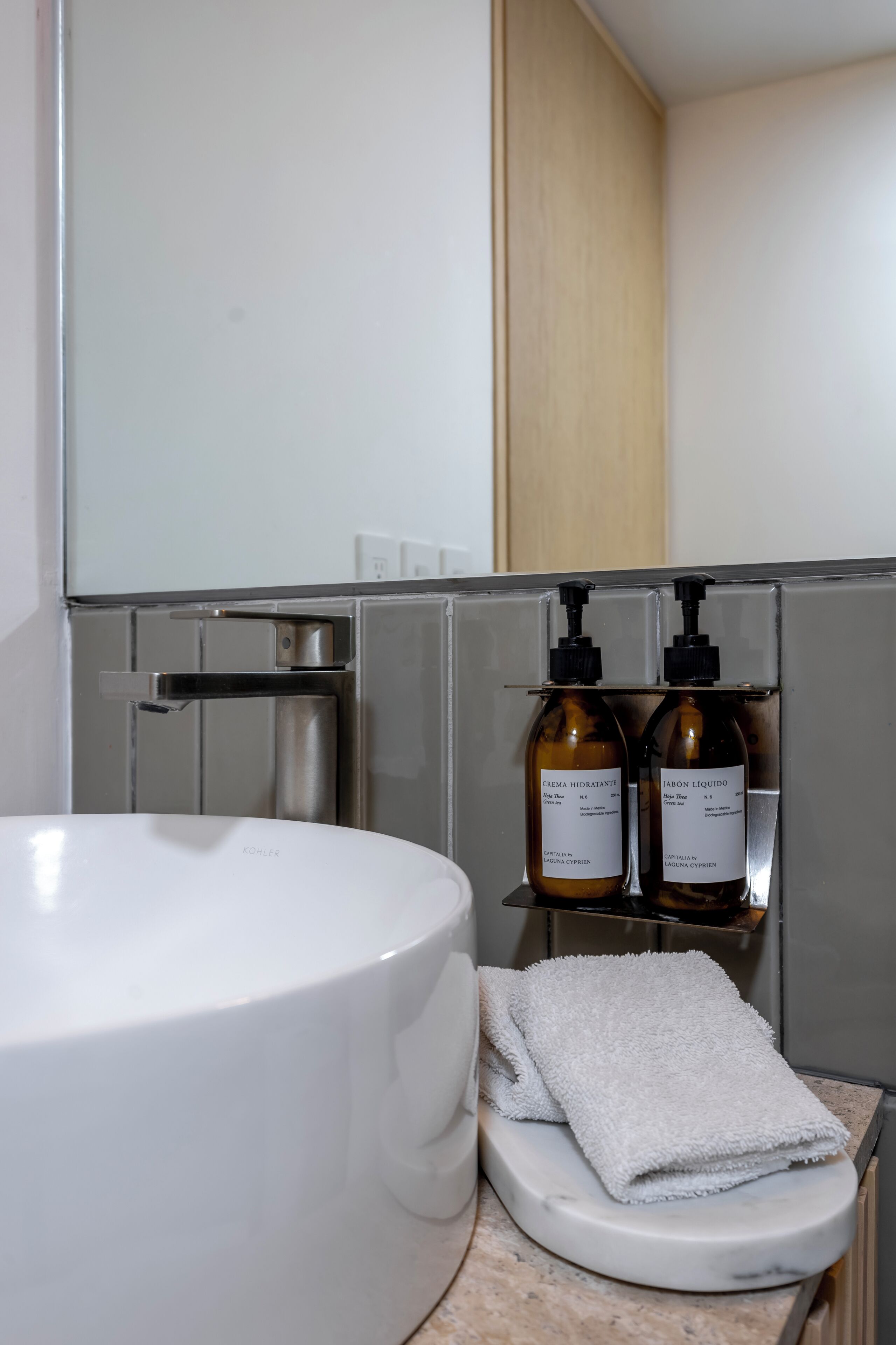 Ein Badezimmer mit einem weißen Waschbecken, einer Toilette und zwei Seifenflaschen auf einem Regal.
