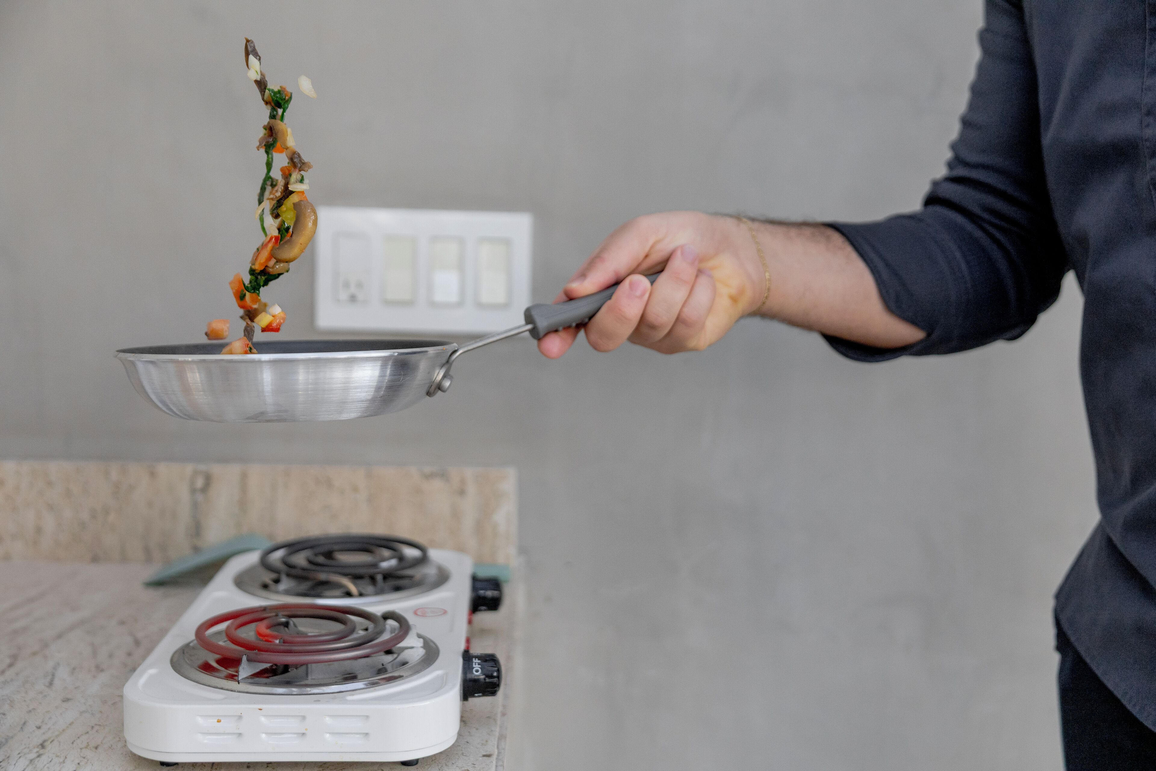 Une personne qui cuisine avec une poêle sur une cuisinière.