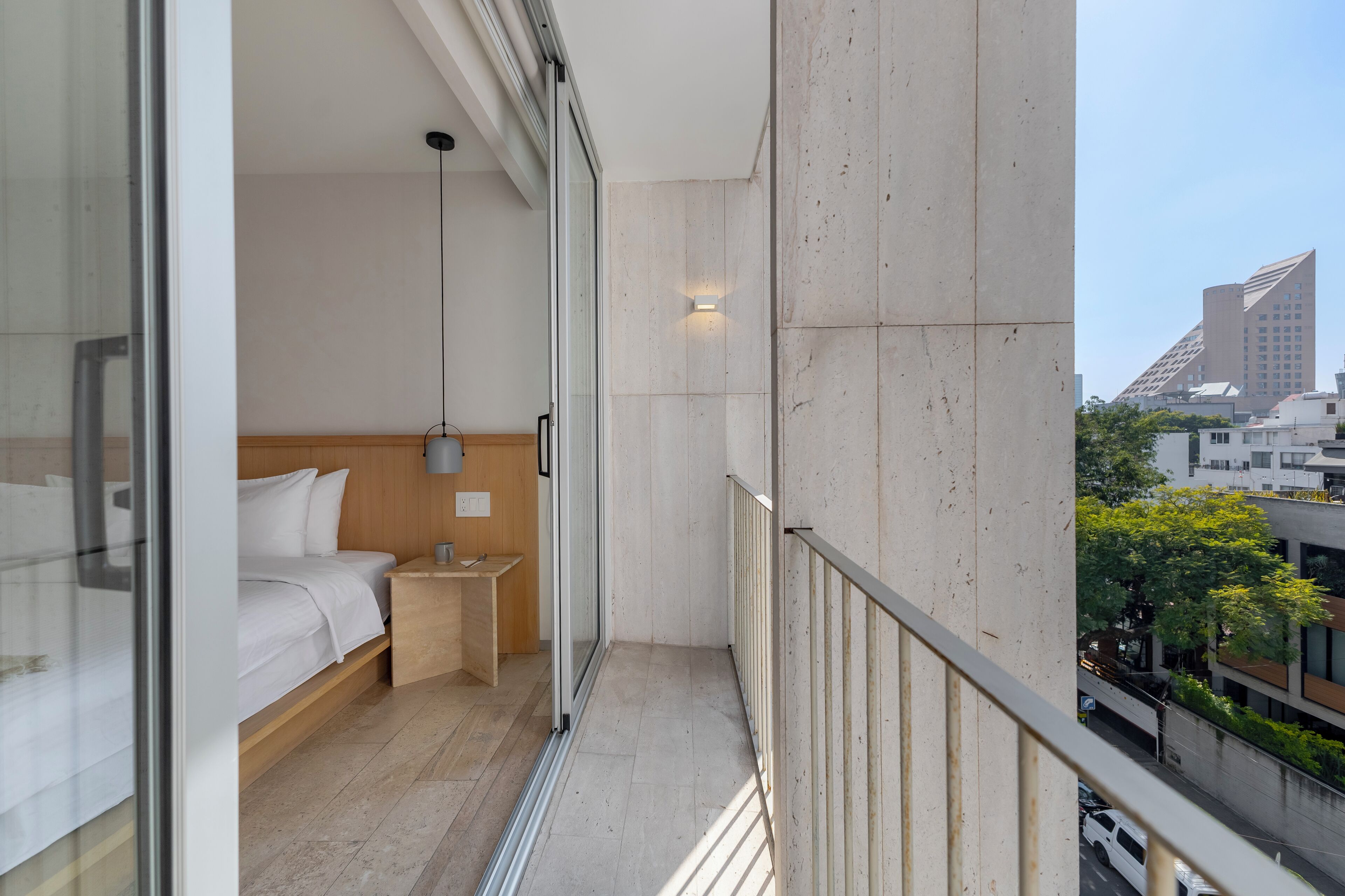 A balcony with a bed, a nightstand, and a view of the cityscape.