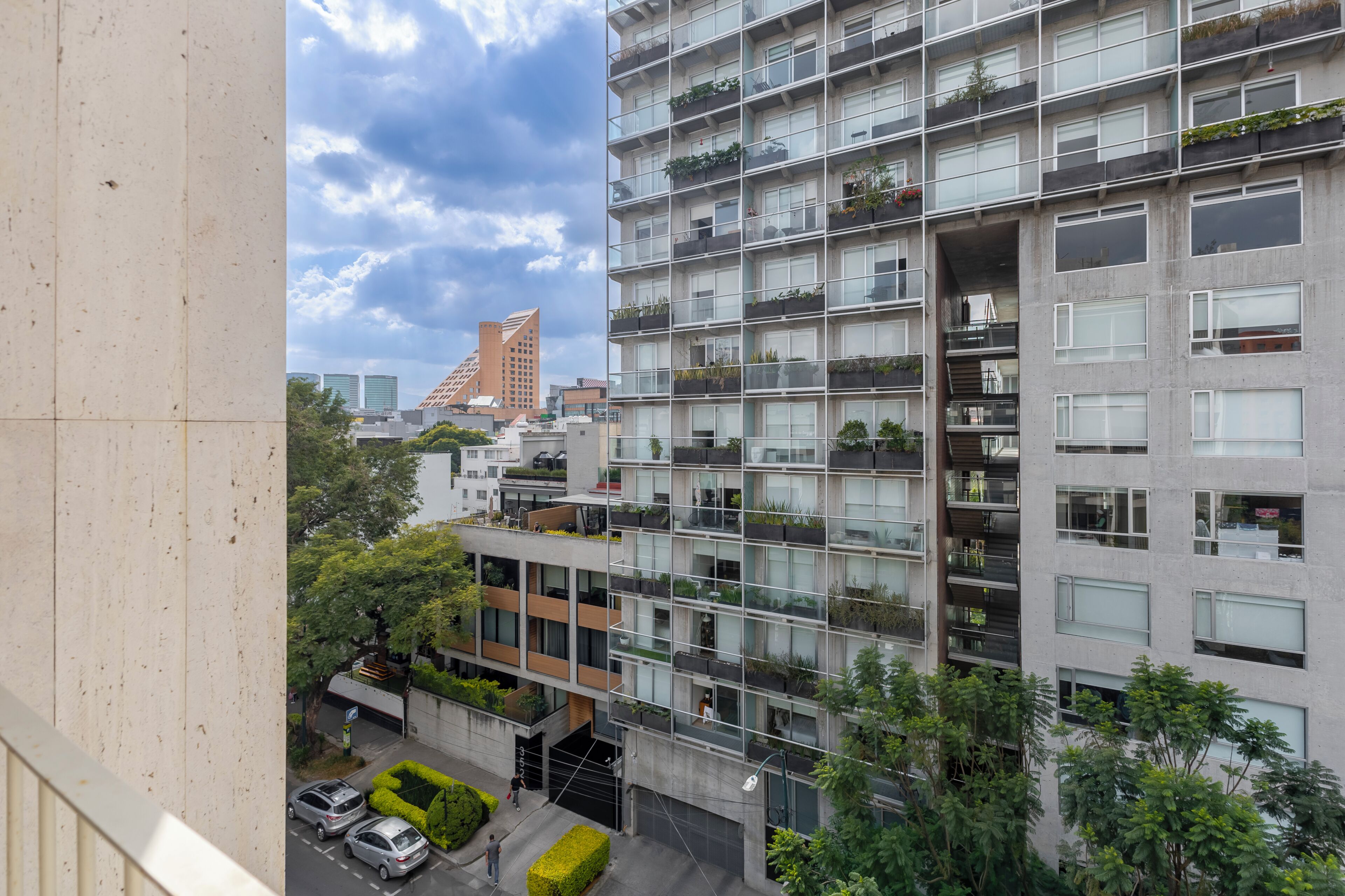 Um edifício de vários andares com varandas, estilo arquitetônico moderno e vista para o horizonte urbano.