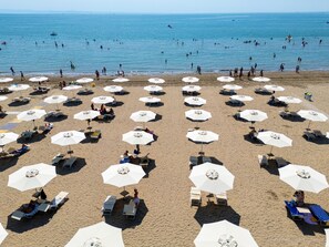 Een strand met rijen ligbedden en parasols, een heldere lucht en de oceaan op de achtergrond.