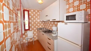 A compact kitchen with a microwave, coffee maker, and a refrigerator.