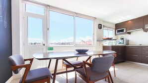 A modern kitchen with a dining area, large windows, and a view of the city. - Principe Real Deluxe by Homing (Lisbon)