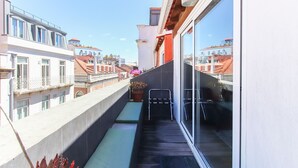 A narrow balcony with a view of adjacent buildings, a potted plant, and a metal chair. - Principe Real Deluxe by Homing (Lisbon)