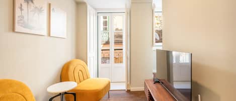 A modern living room with a sofa, a small table, a TV, and a wooden cabinet.
