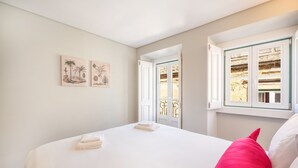 A bedroom with a bed, a window with a view, and two wall-mounted artworks. - Bairro Alto Prime Studio II by Homing (Lisbon)