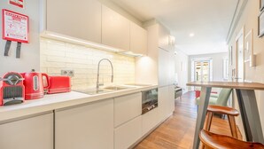 A modern kitchen with white cabinets, a stainless steel sink, and a red coffee maker. - Bairro Alto Prime Studio II by Homing (Lisbon)