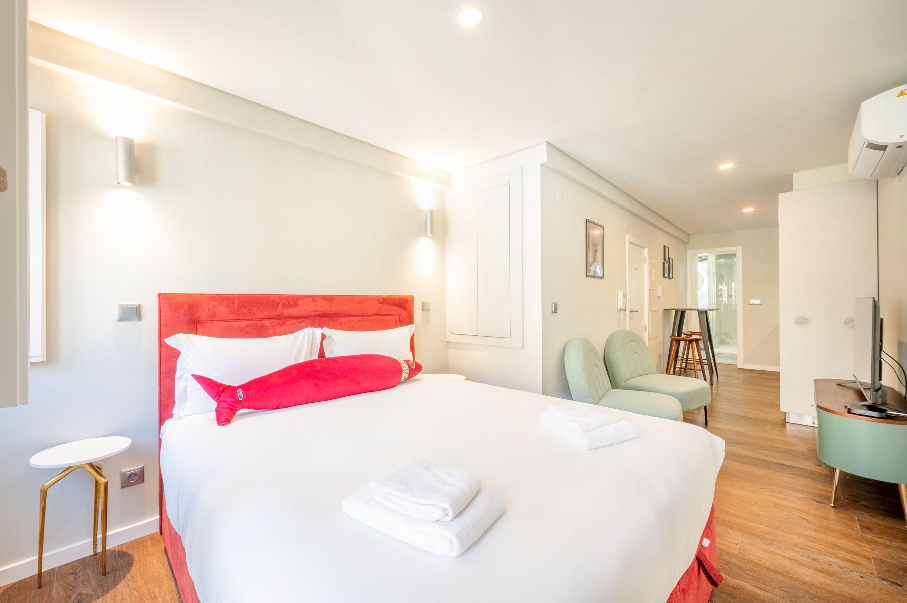 A modern hotel room with a large bed, a small table, a chair, and a TV.