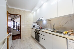 Une cuisine moderne équipée d’un four, d’un micro-ondes et d’un évier intégrés.