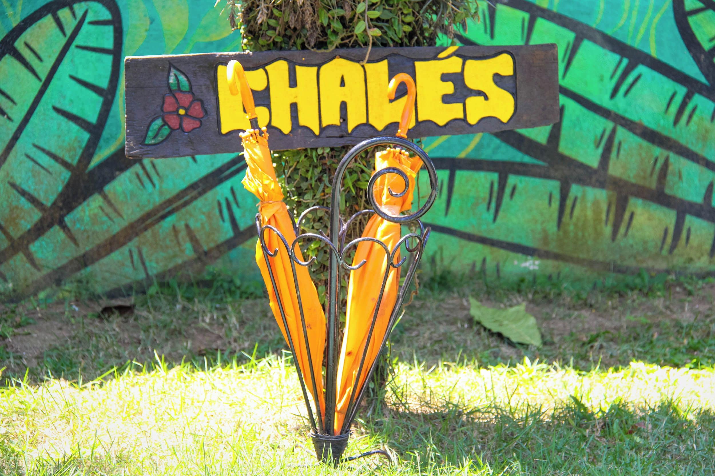 A sign with the word 'CHALLES' and a flower design, mounted on a metal structure with two umbrellas.