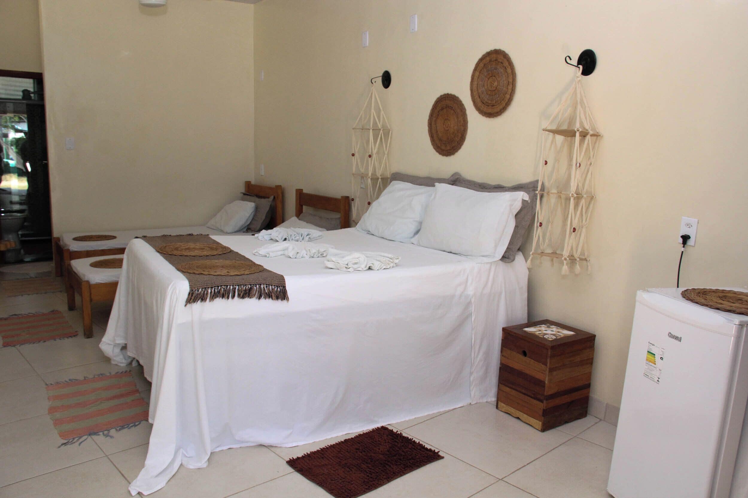 A bedroom with two beds, a refrigerator, and a bedside table.