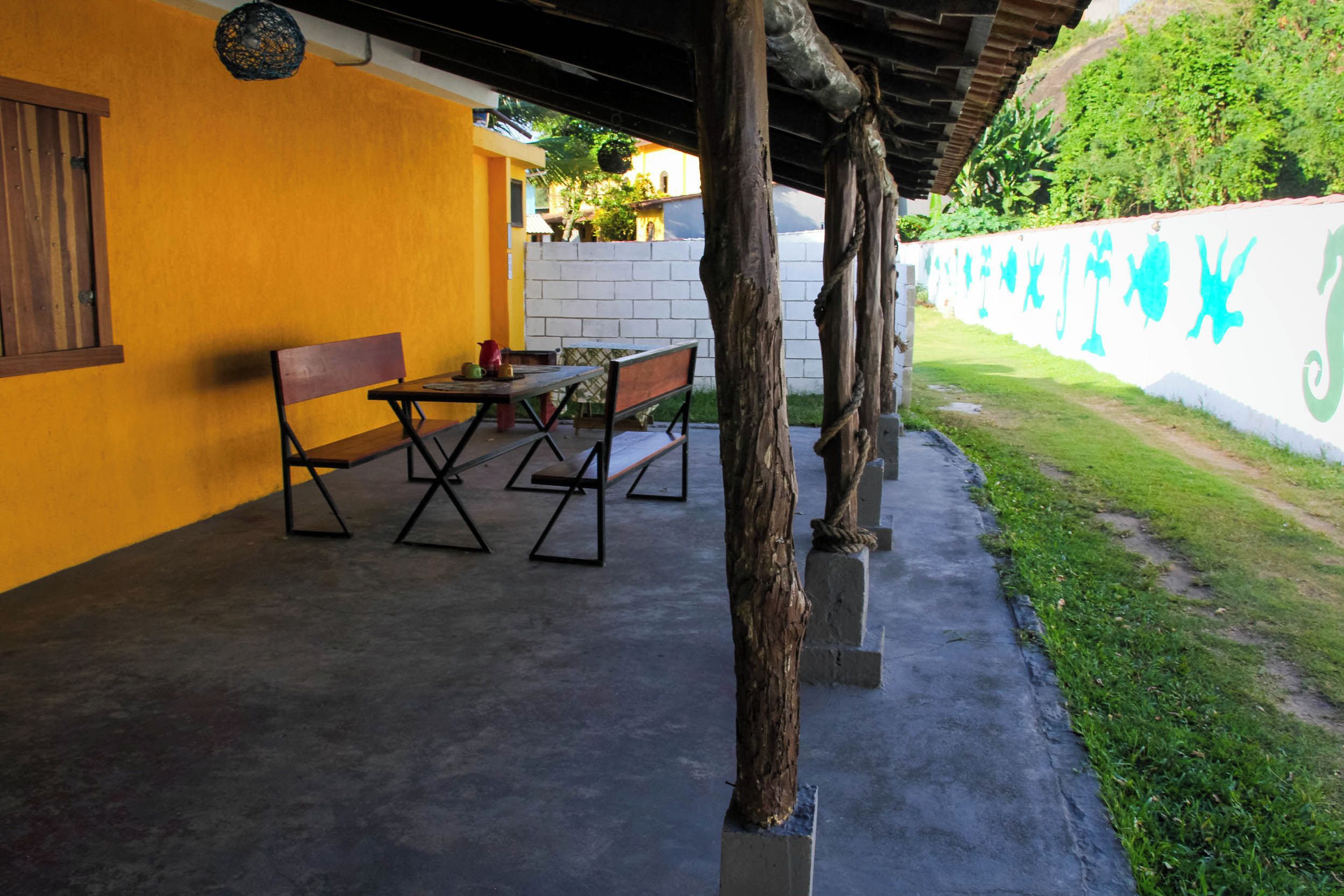 Une terrasse extérieure avec une table et des chaises, un banc en bois et un sol en béton.