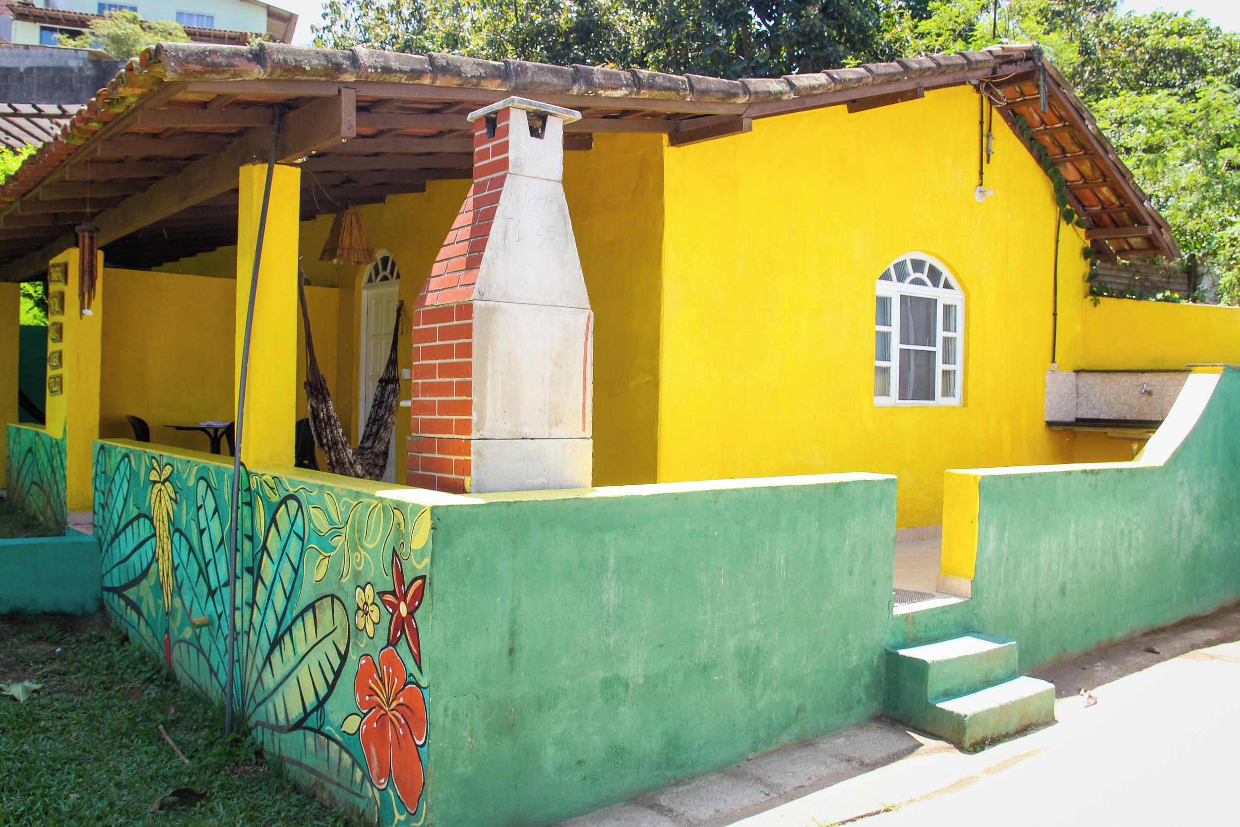 Un edificio amarillo con revestimiento verde y una chimenea de ladrillo.
