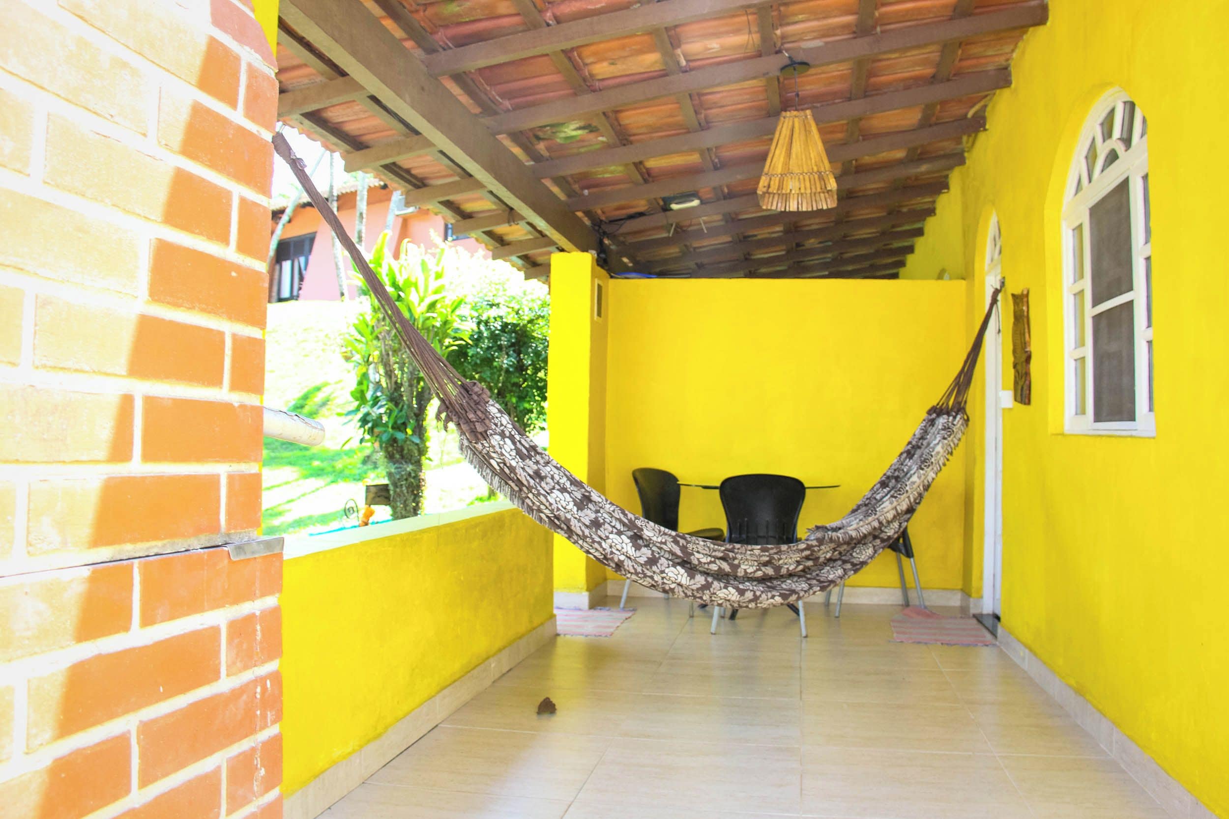 Una habitación con una hamaca, una mesa, sillas y un ventanal.