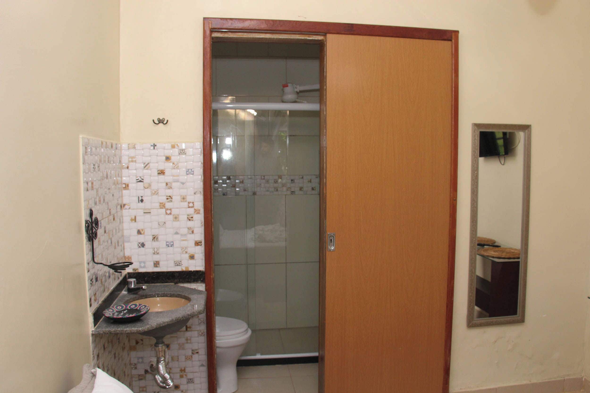 Un baño con pared de azulejos, un lavamanos, un inodoro y una zona de ducha.