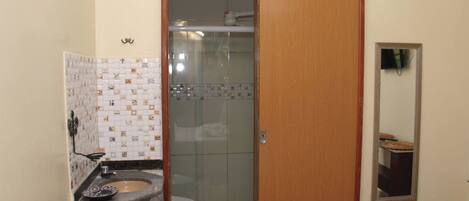 Un baño con pared de azulejos, un lavamanos, un inodoro y una zona de ducha.