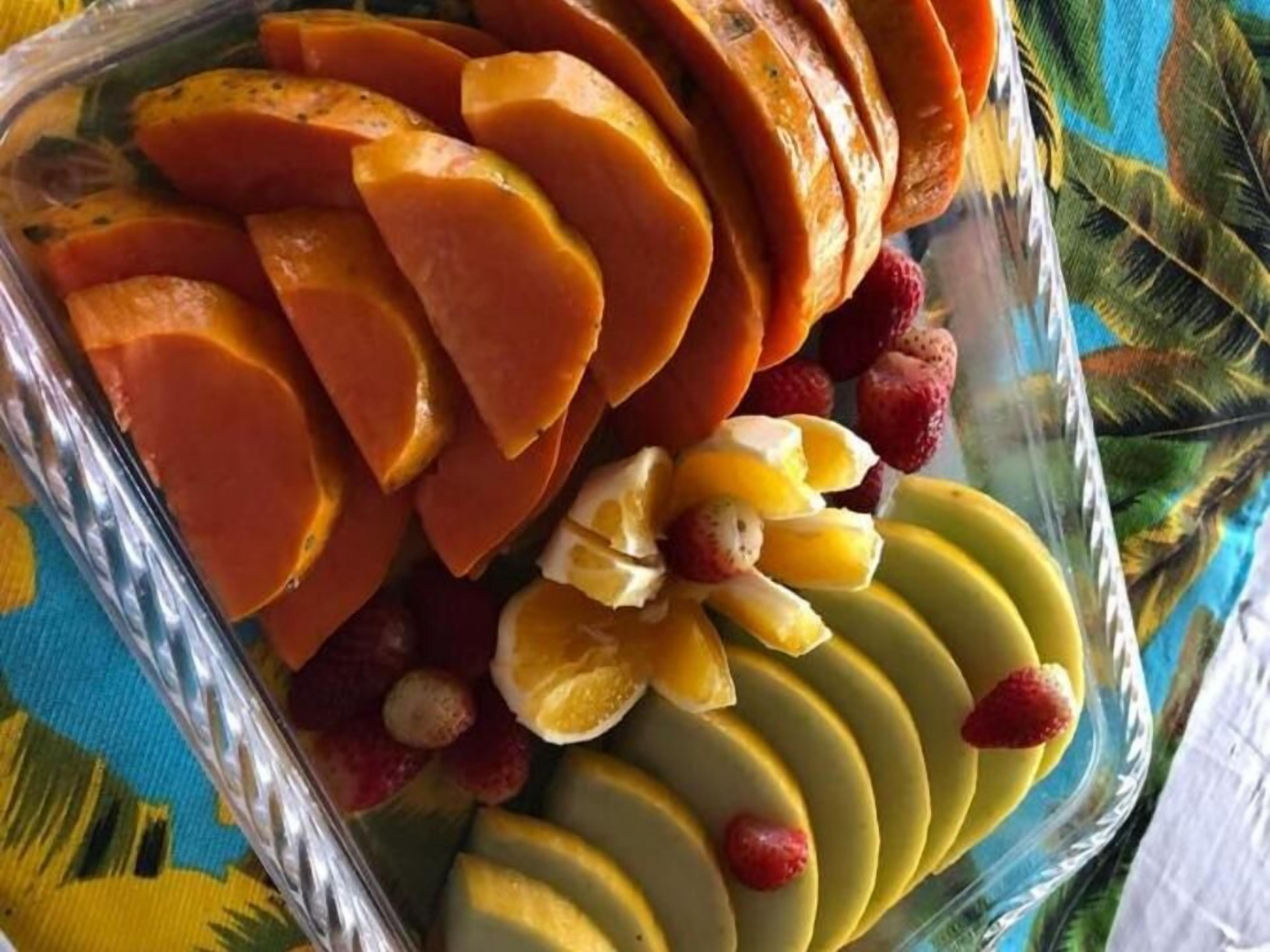 A glass dish containing sliced fruits and berries.
