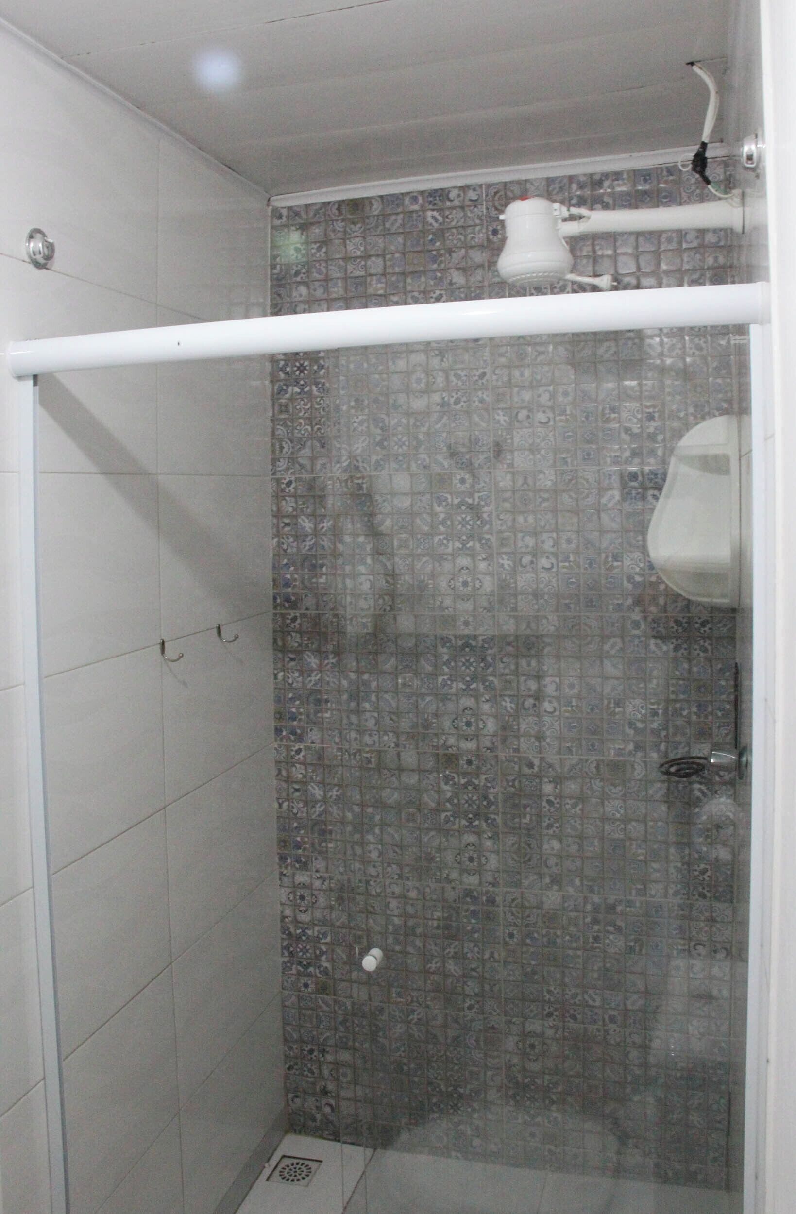 Une douche avec une porte en verre, des murs carrelés et un porte-serviettes blanc.