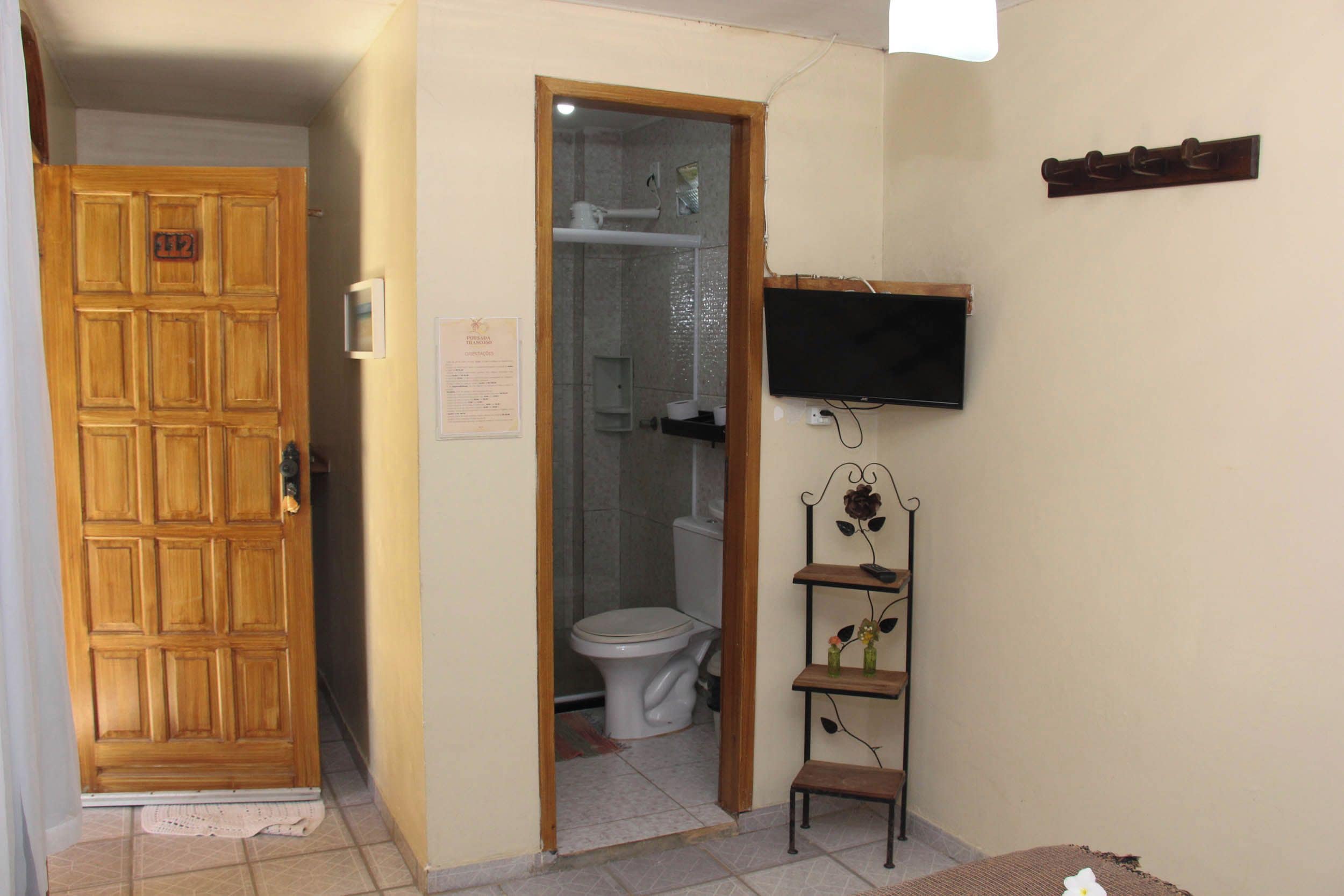 A bathroom with a toilet, a shower, and a television mounted on the wall.