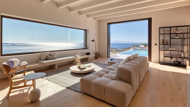 A modern living room with a large window overlooking a pool and the sea. - Villa in Mykonos with 5 bedrooms sleeps 10 (Mykonos)